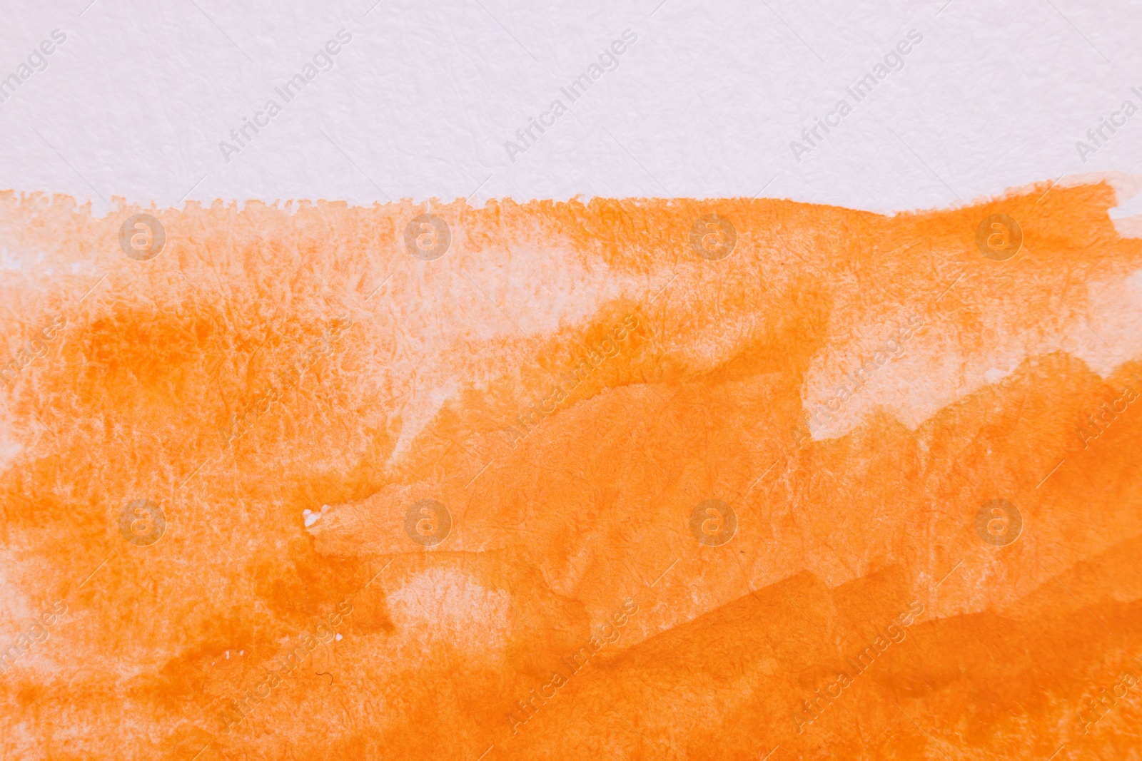 Photo of Abstract orange watercolor painting on white paper, top view