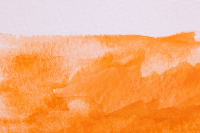 Abstract orange watercolor painting on white paper, top view