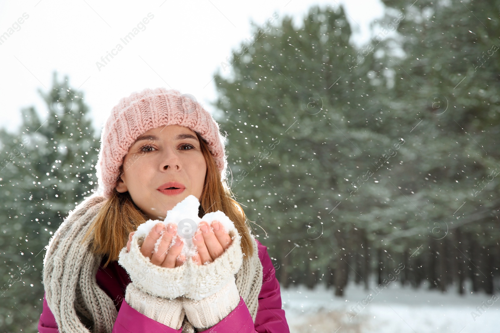 Photo of Beautiful woman blowing snow in winter forest. Space for text