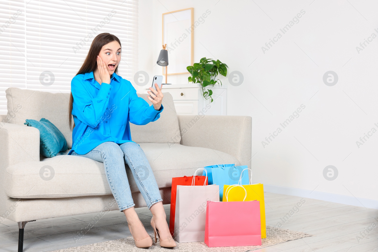 Photo of Special Promotion. Emotional woman with smartphone on sofa indoors, space for text