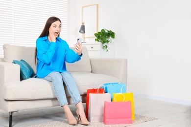 Photo of Special Promotion. Emotional woman with smartphone on sofa indoors, space for text