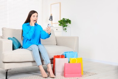 Special Promotion. Emotional woman with smartphone on sofa indoors, space for text