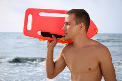 Photo of Handsome lifeguard with life buoy near sea