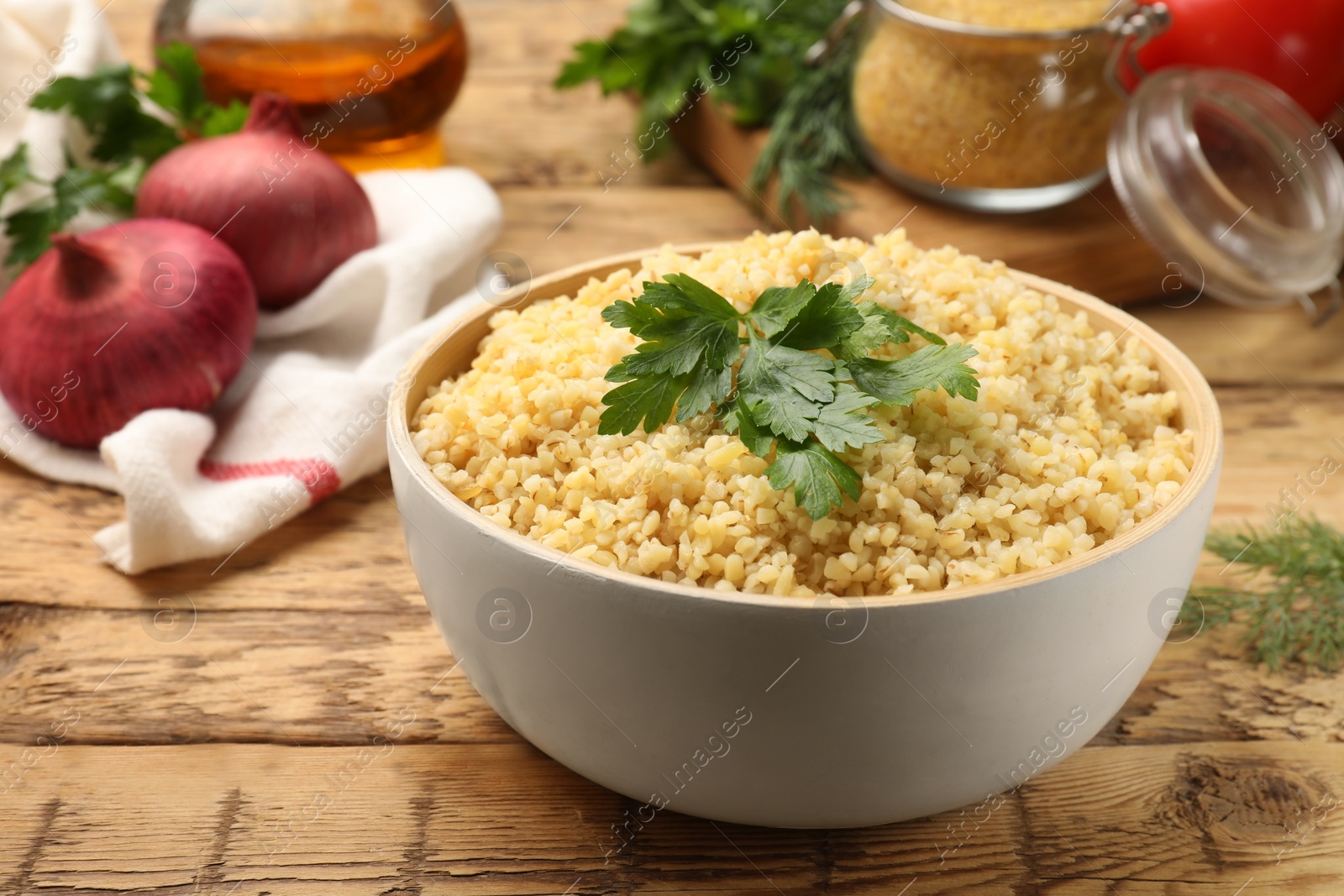 Photo of Delicious bulgur with parsley on wooden table, closeup