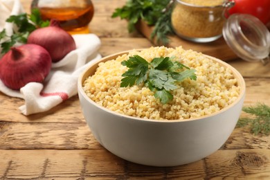 Photo of Delicious bulgur with parsley on wooden table, closeup