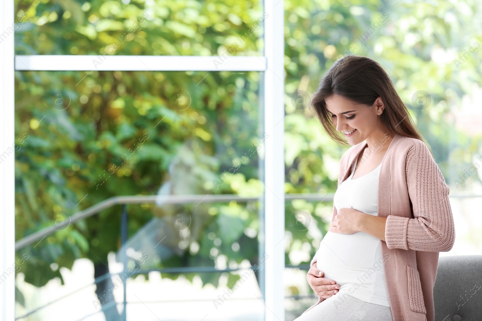 Photo of Happy pregnant woman near window at home