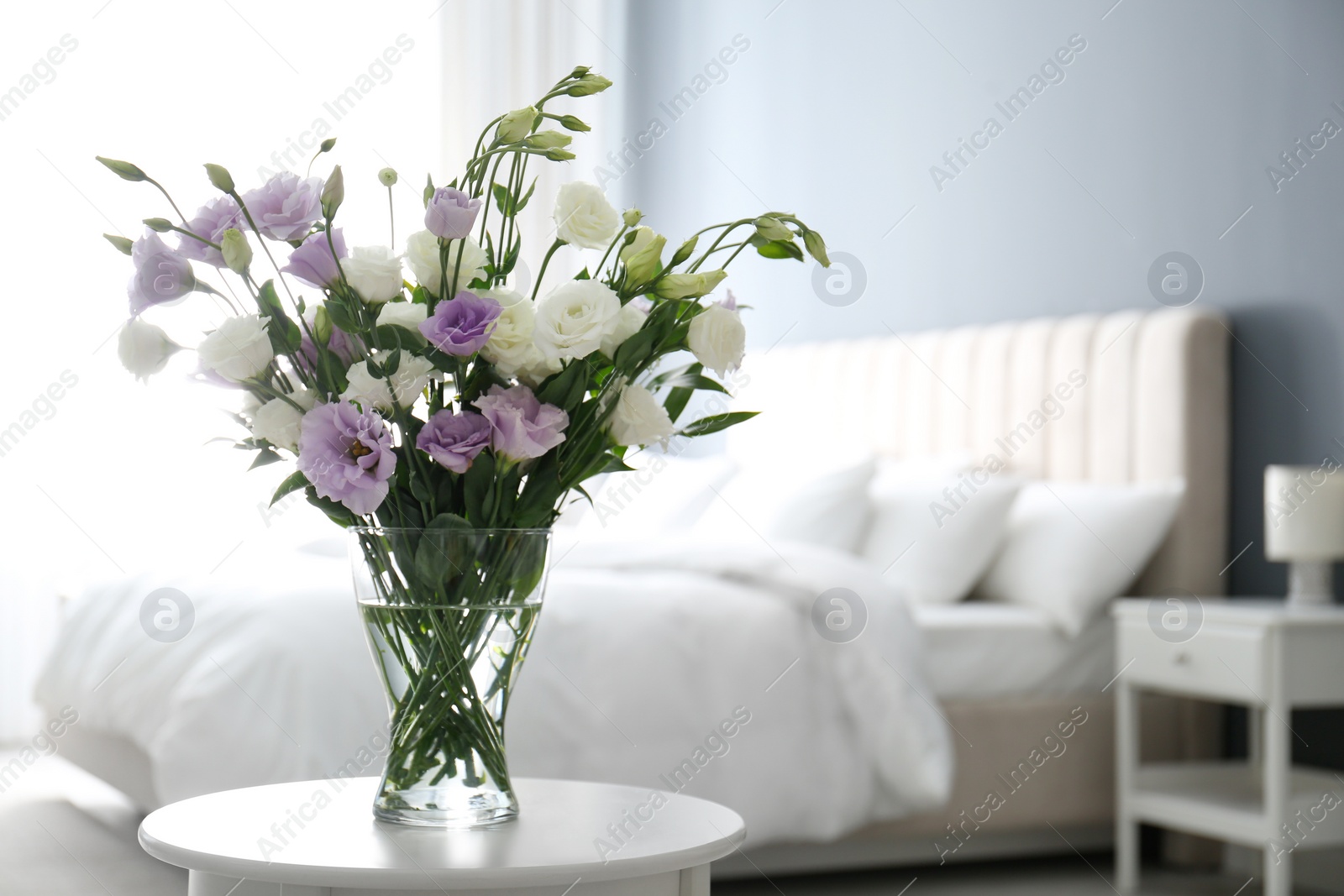 Photo of Beautiful bouquet with Eustoma flowers on table in bedroom. Space for text