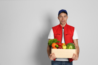 Courier with fresh products on light background, space for text. Food delivery service