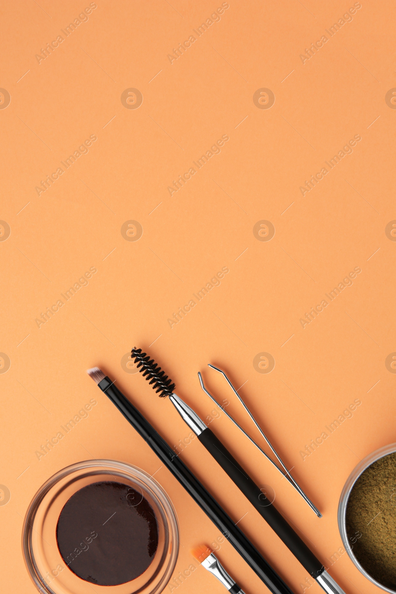 Photo of Flat lay composition with eyebrow henna and professional tools on orange background, space for text