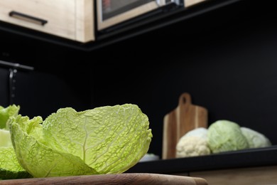 Photo of Fresh Savoy cabbage leaves on wooden board in kitchen, space for text