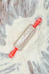 Photo of Flour and rolling pin on wooden table, top view