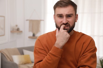 Photo of Man biting his nails indoors, space for text. Bad habit