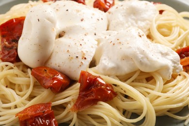 Photo of Delicious spaghetti with burrata cheese and sun dried tomatoes on plate, closeup