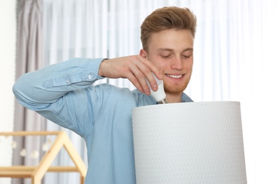 Man changing light bulb in lamp indoors