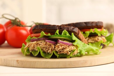 Photo of Delicious sandwiches with tuna and vegetables on white table. closeup