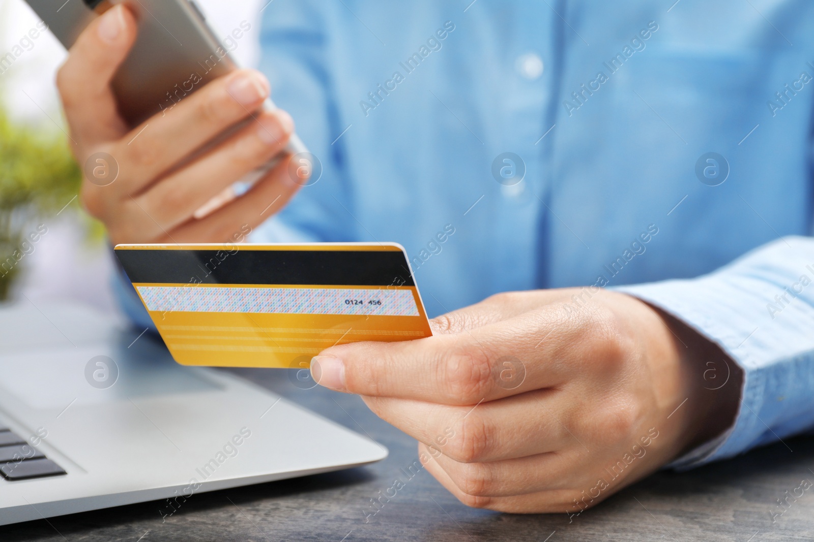 Photo of Young woman with credit card using smartphone at table