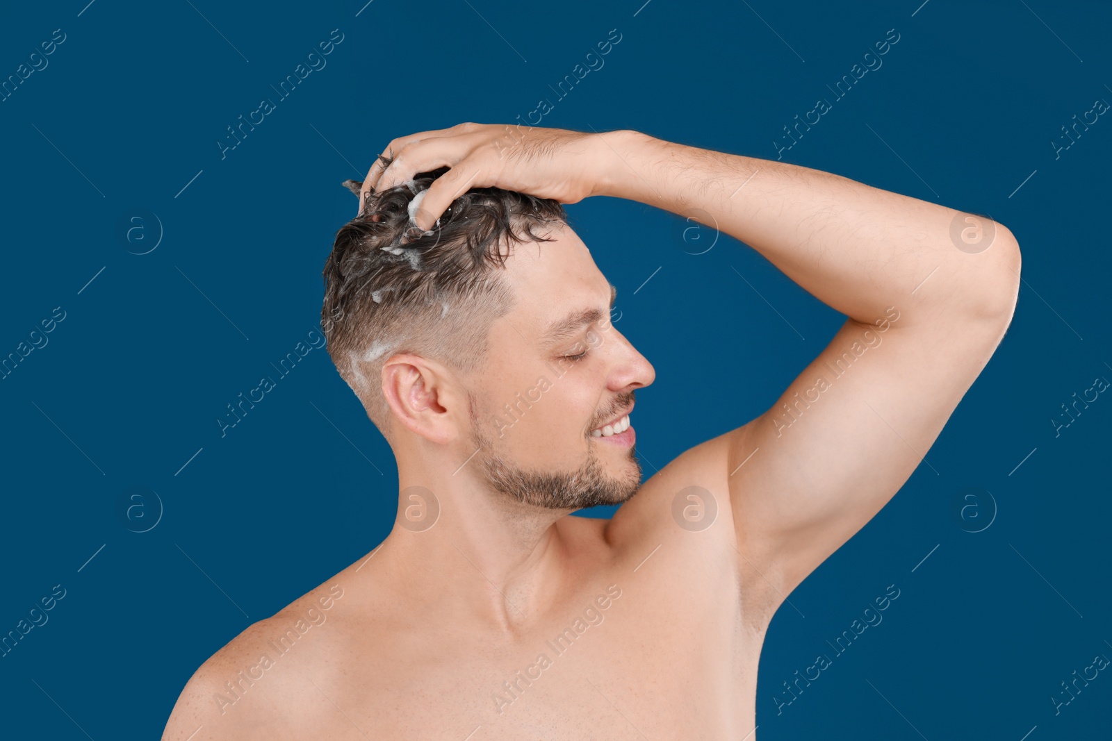 Photo of Handsome man washing hair on blue background