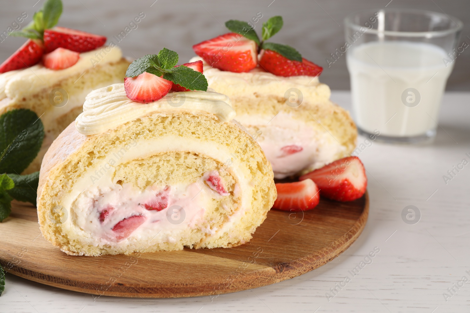 Photo of Delicious cake roll with strawberries and cream on wooden board, closeup