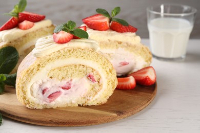 Delicious cake roll with strawberries and cream on wooden board, closeup