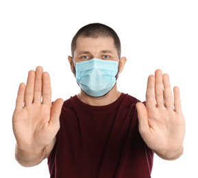 Photo of Man in protective mask showing stop gesture on white background. Prevent spreading of coronavirus