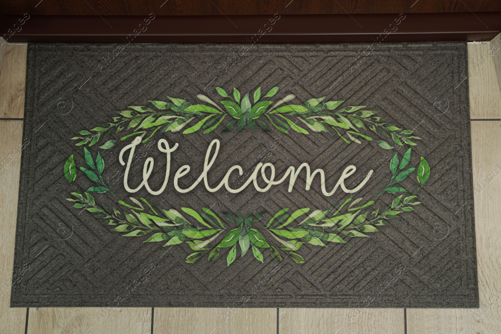 Photo of Beautiful doormat with word Welcome on floor near entrance, top view