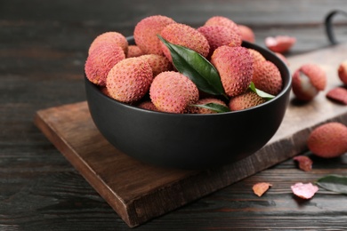 Fresh ripe lychee fruits in bowl on dark wooden table