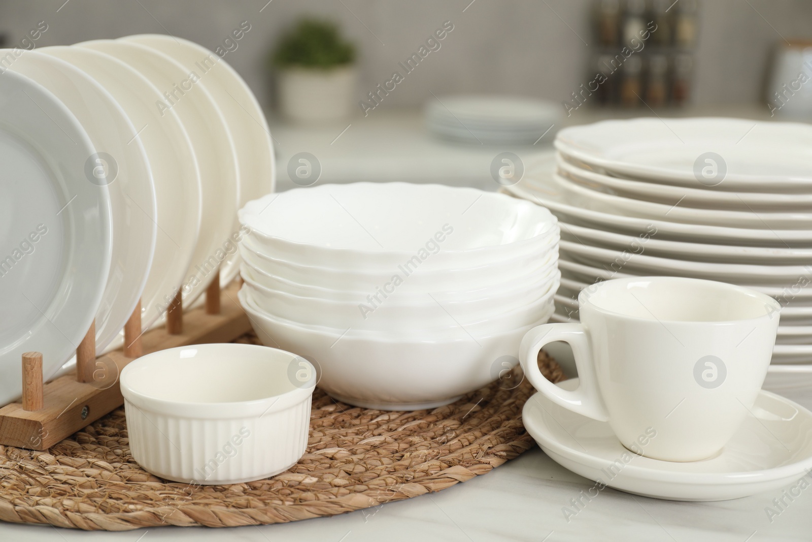 Photo of Clean plates, bowls and cup on white marble table in kitchen