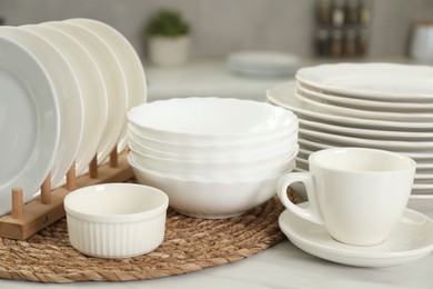 Clean plates, bowls and cup on white marble table in kitchen