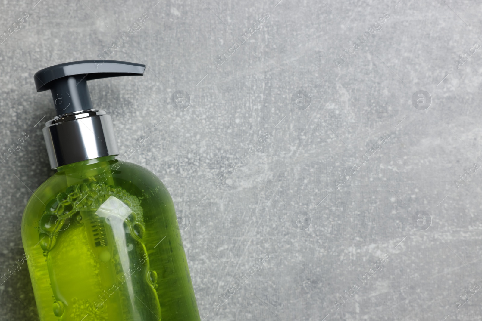 Photo of Dispenser of liquid soap on grey table, top view. Space for text