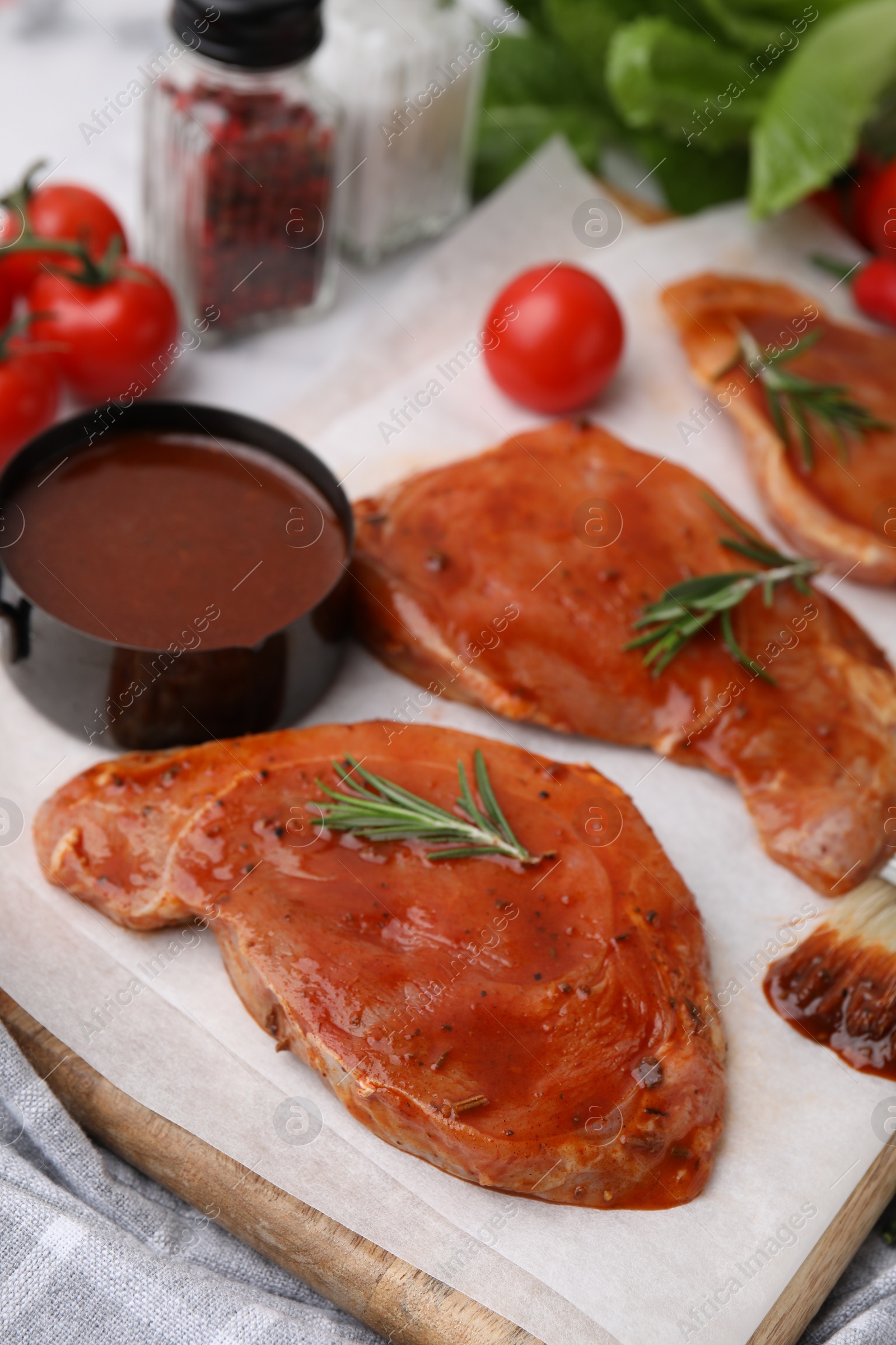 Photo of Raw marinated meat and rosemary on table, closeup