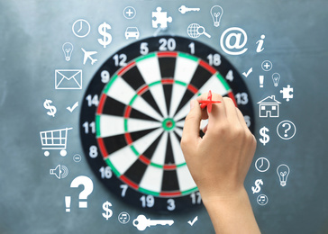 Image of Woman throwing darts at board on grey background, closeup