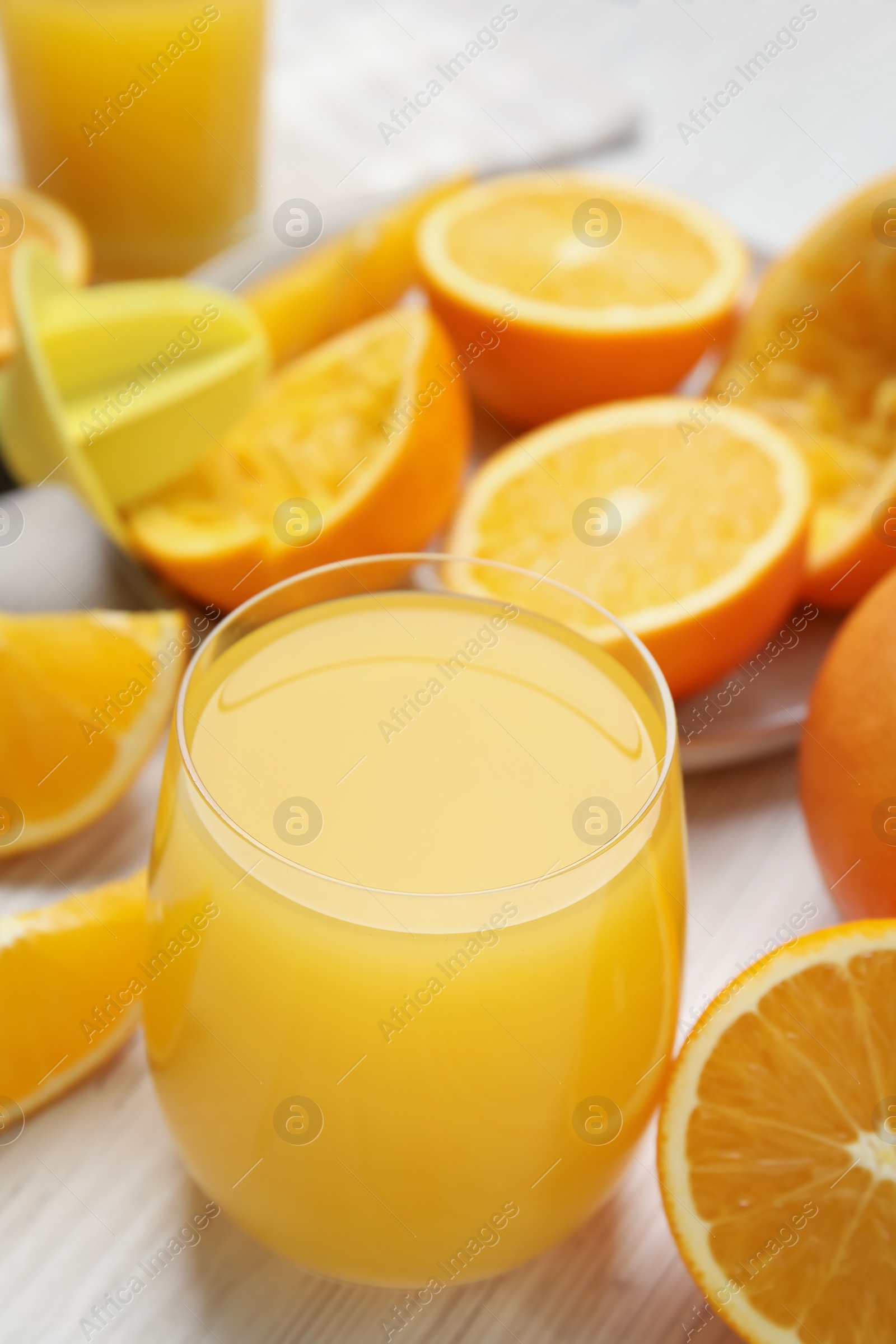 Photo of Freshly made juice, oranges and reamer on wooden table