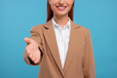 Photo of Woman welcoming and offering handshake on light blue background, closeup