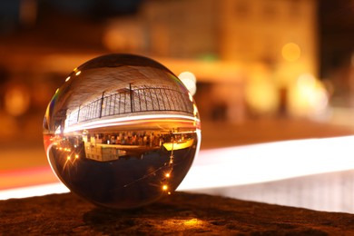 Photo of Beautiful city street, overturned reflection. Crystal ball at night, closeup. Space for text