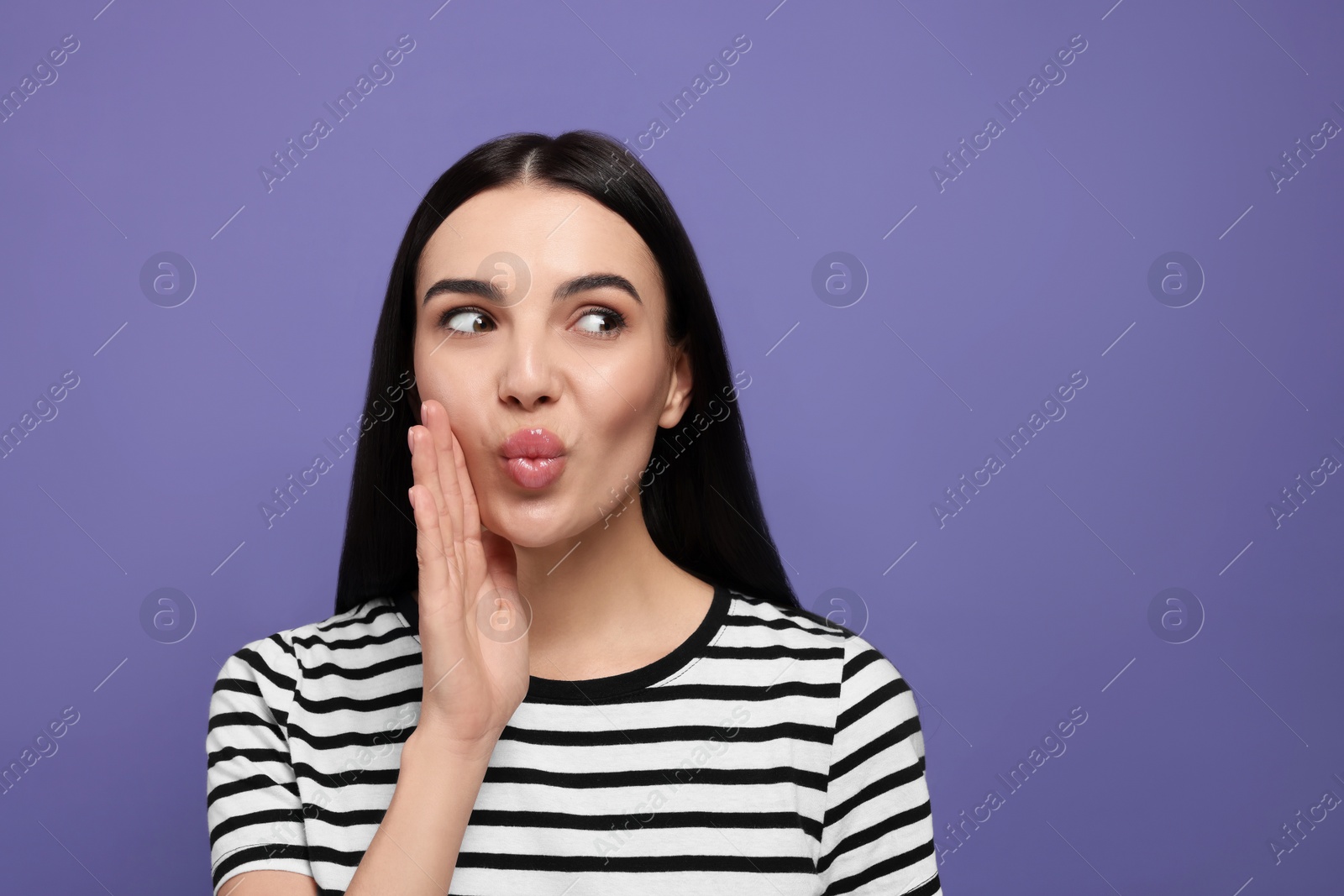 Photo of Beautiful young woman blowing kiss on purple background