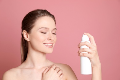 Photo of Young woman with bottle of thermal water on color background. Cosmetic product