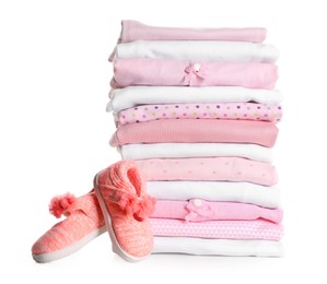 Photo of Stack of clean girl's clothes and booties on white background