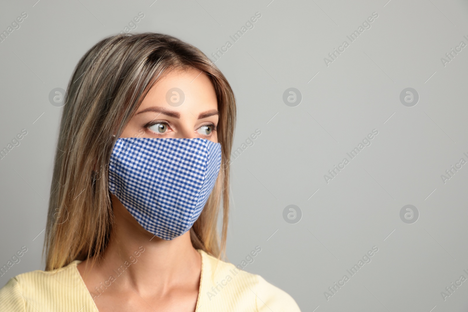 Photo of Young woman in protective face mask on light grey background. Space for text