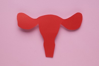 Woman`s health. Paper uterus on pale pink background, top view