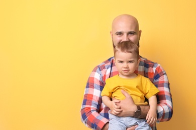 Portrait of dad and his little son on color background