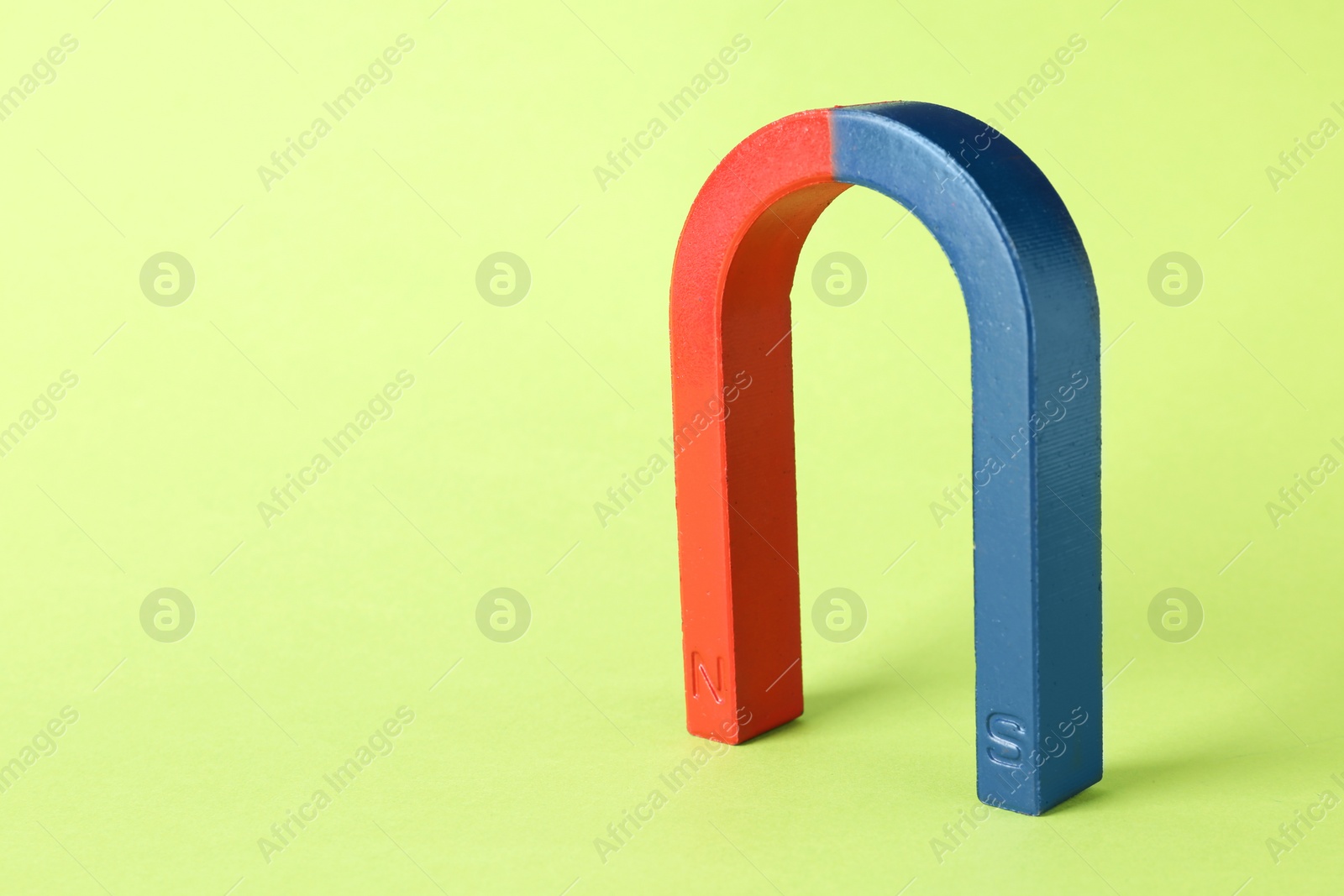 Photo of Red and blue horseshoe magnet on color background. Space for text