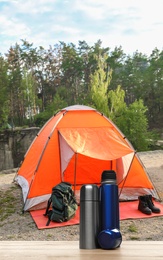 Image of Modern thermo bottles outdoors. Camping season 