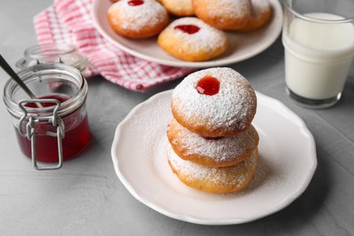 Photo of Hanukkah donuts with jelly and powdered sugar served on light grey table