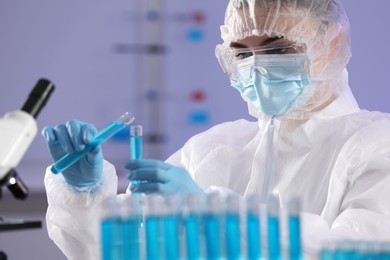 Photo of Scientist working with test tubes of light blue liquid in laboratory