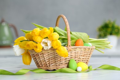 Easter basket with bouquet of tulips and eggs on white marble table indoors