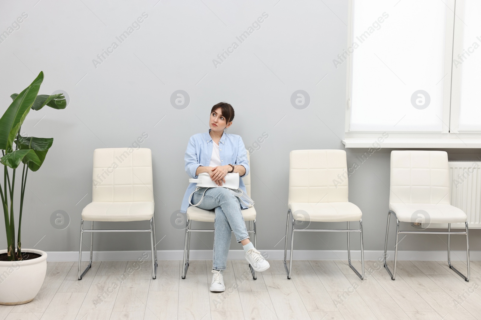 Photo of Woman sitting on chair and waiting for appointment indoors