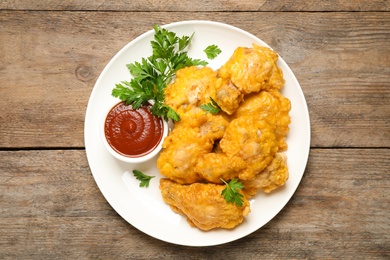 Photo of Tasty deep fried chicken pieces served on wooden table, top view