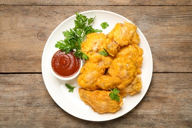 Tasty deep fried chicken pieces served on wooden table, top view