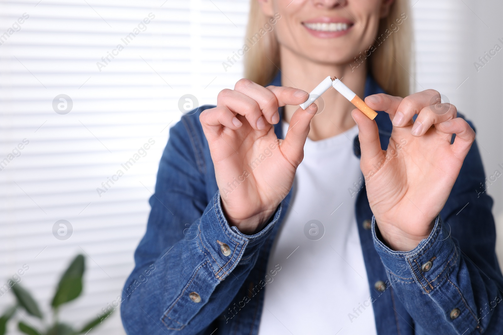 Photo of Woman breaking cigarette on blurred background, closeup. Stop smoking concept