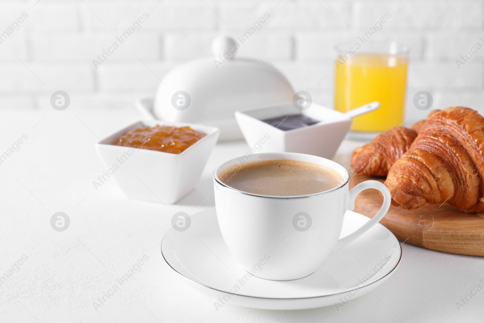 Photo of Fresh croissants, jams and coffee on white table. Tasty breakfast